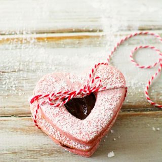 Heart shaped pink linzer cookies tied by a string.