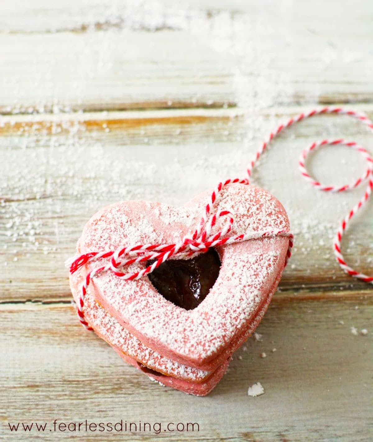 The heart shaped pink linzer cookies tied by a string.