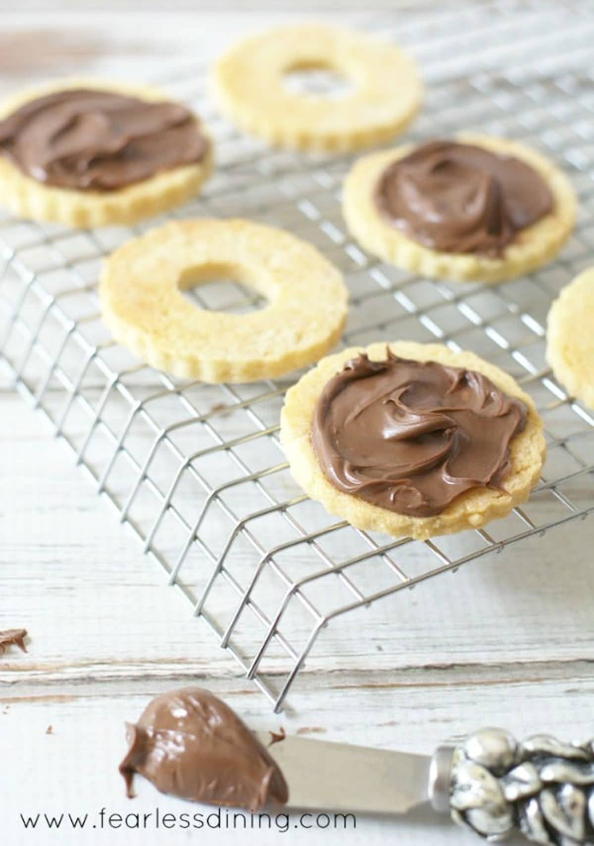 Spreading Nutella on the linzer cookie bottoms.