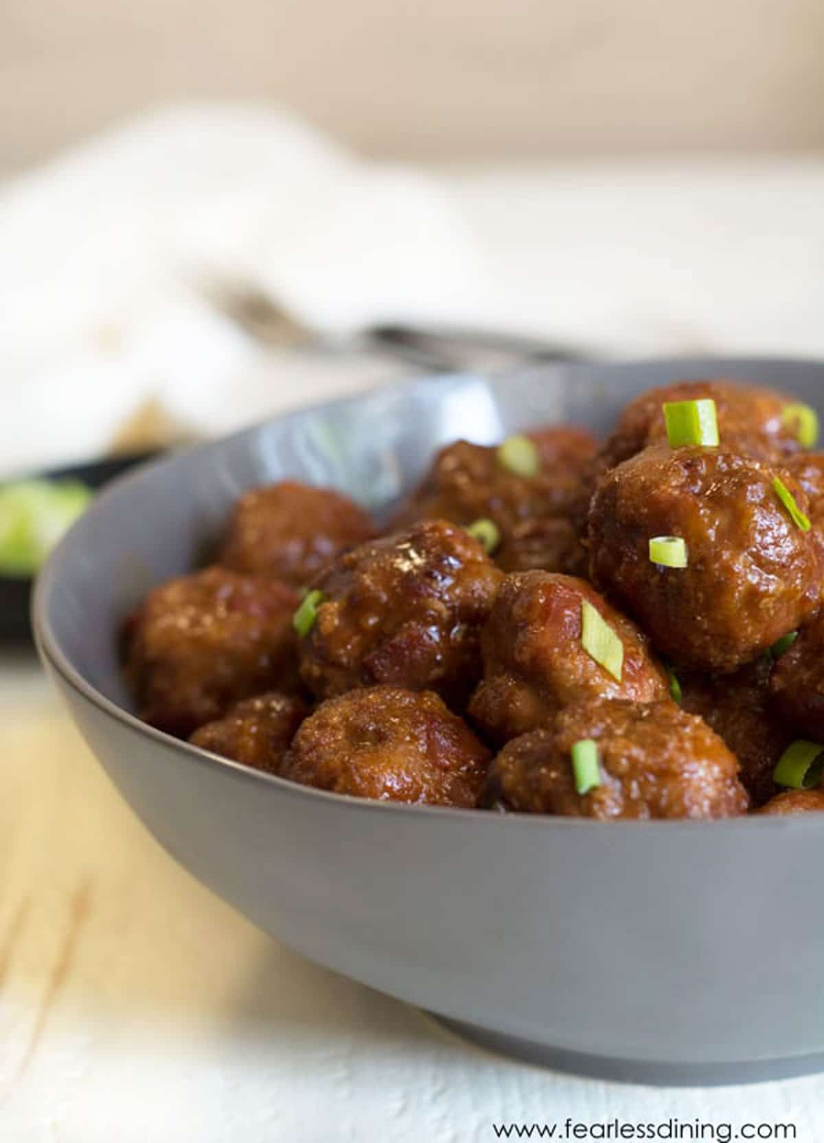 A grey bowl filled with BBQ meatballs.