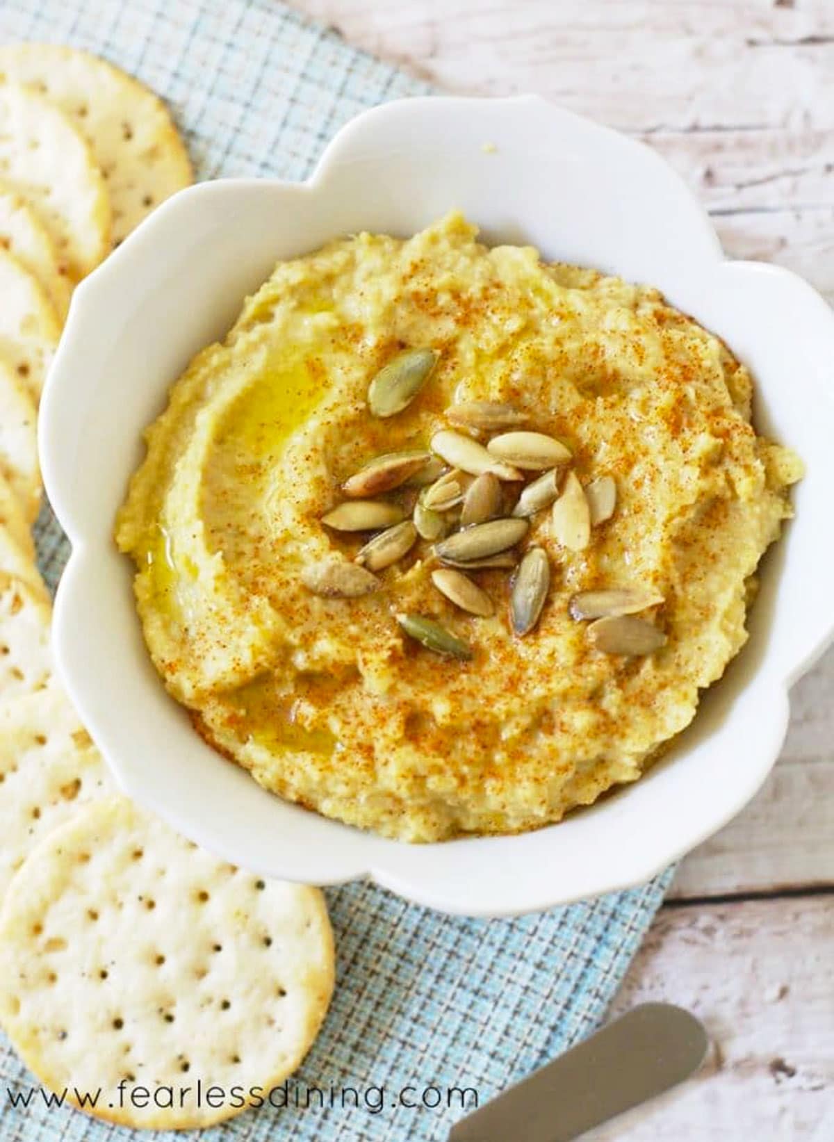 A bowl of hatch chile hummus next to crackers.