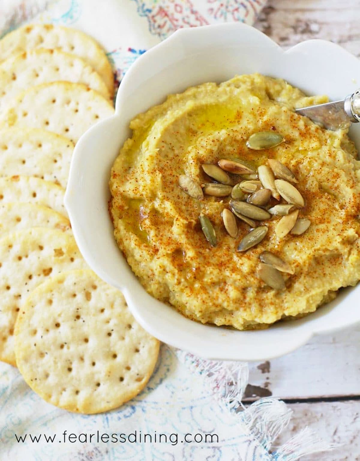 Another shot of the bowl of hatch chili hummus next to crackers.