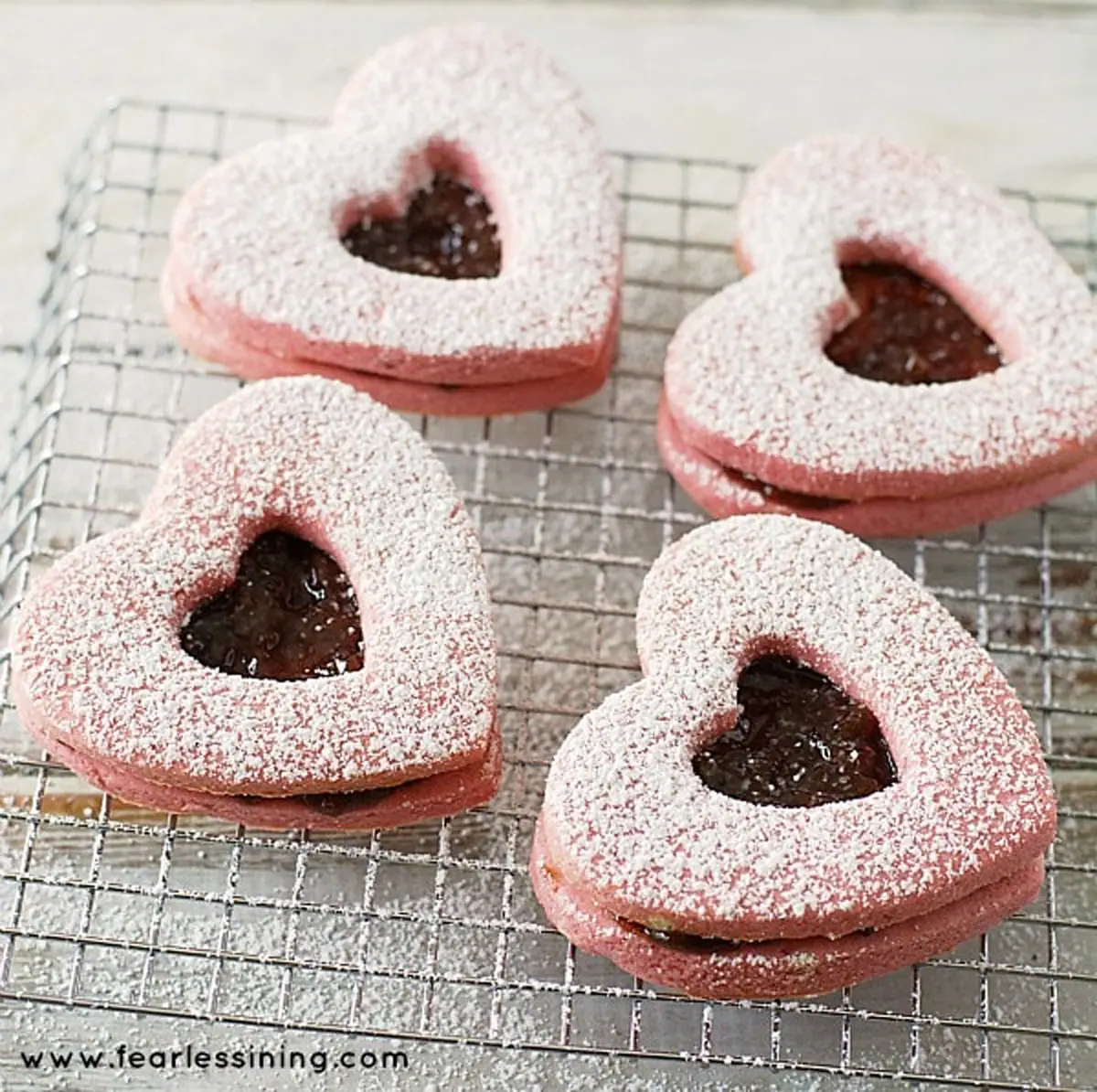 powdered sugared dusted linzer cookies on a rack