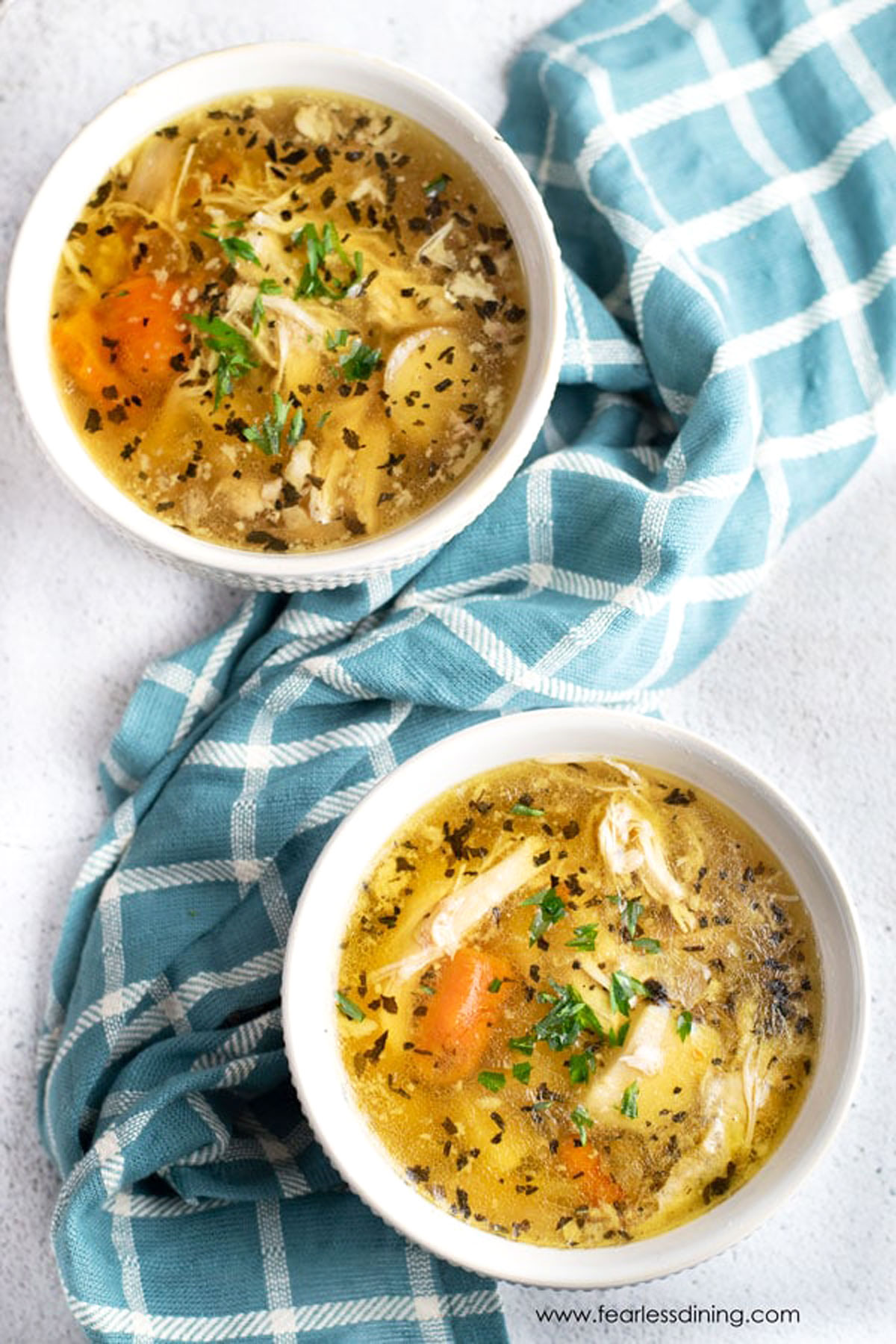 Two bowls of soup next to a blue napkin.