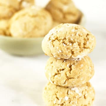 A stack of honey cookies next to a bowl of cookies.