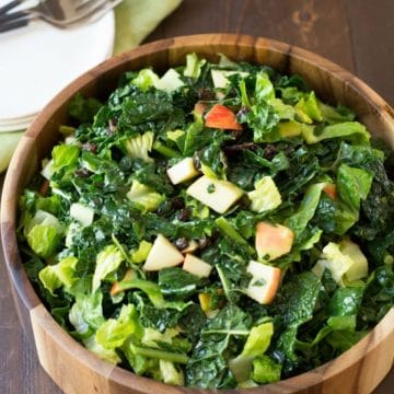 A wooden salad serving bowl filled with kale salad.