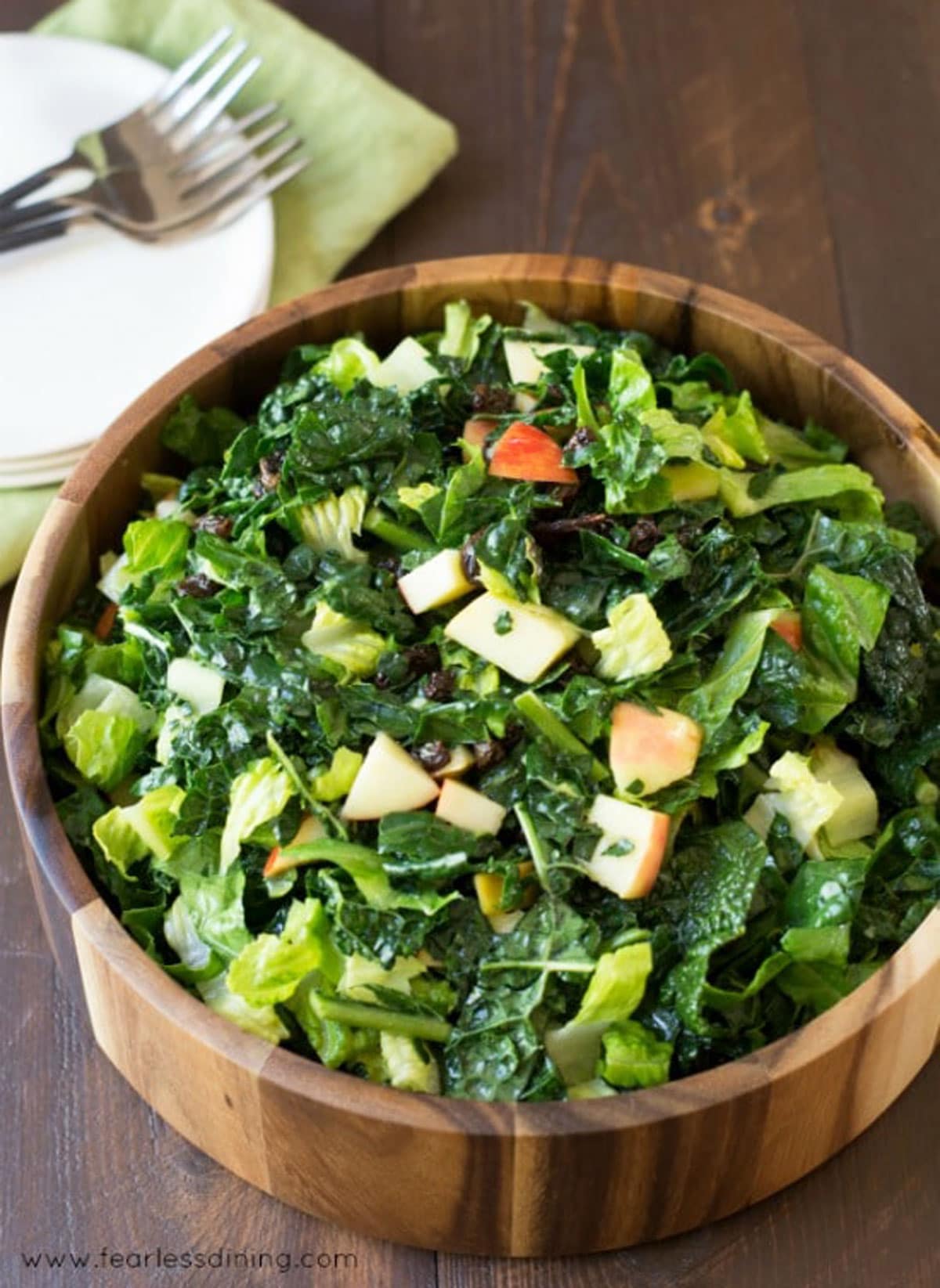 A wooden salad serving bowl filled with kale salad.