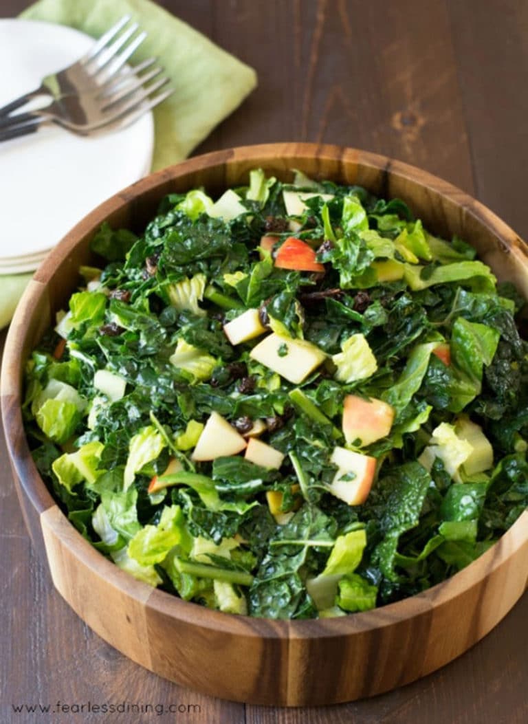A close up of the kale and apple salad in a wooden bowl.