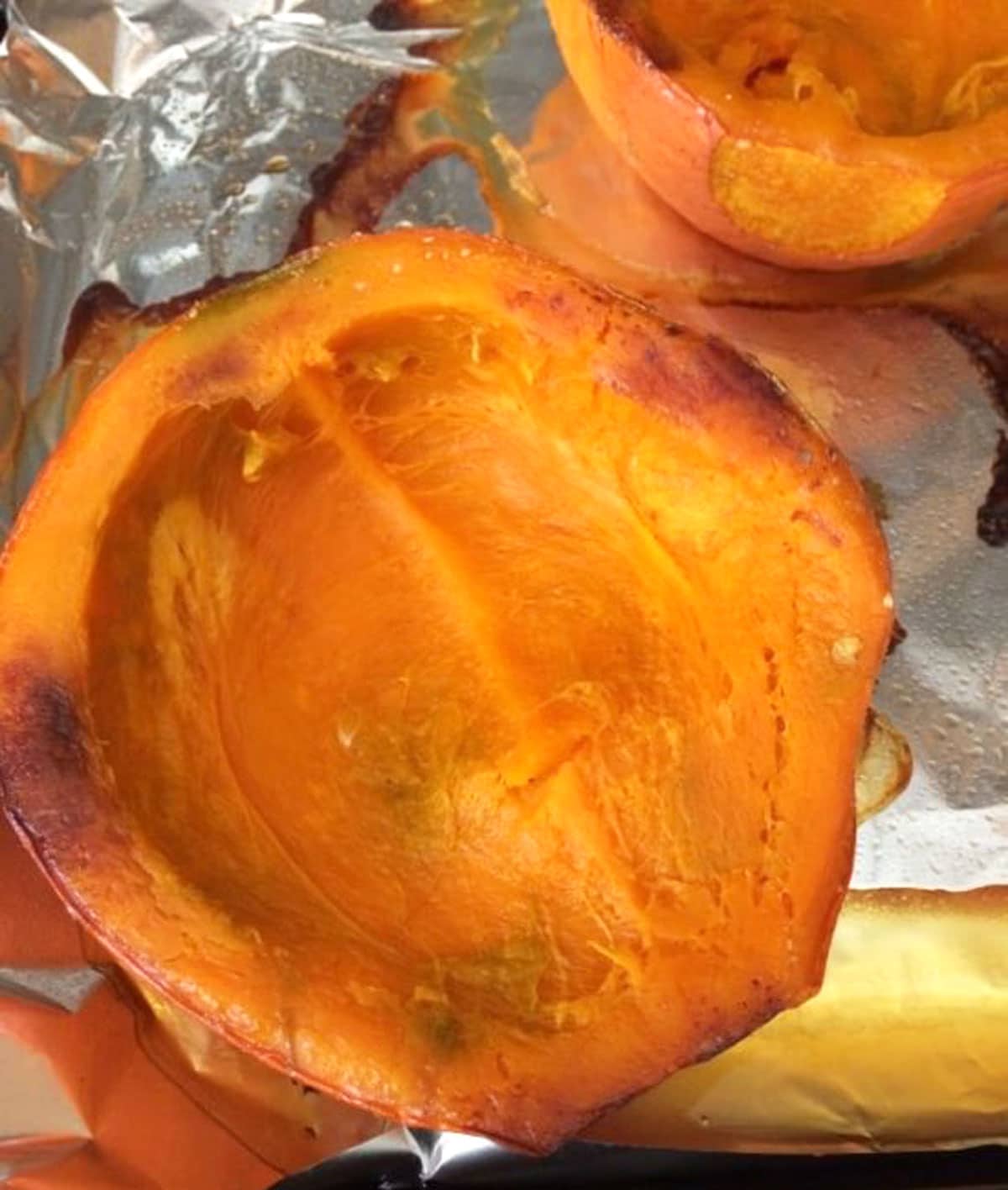 Half of a roasted kuri squash on a baking sheet.