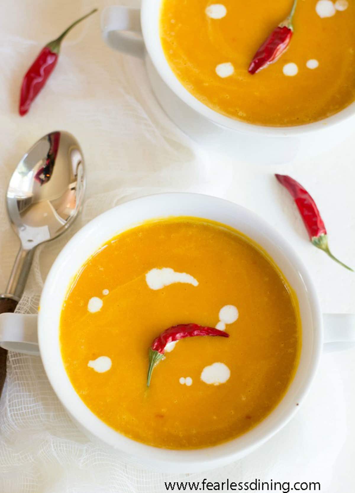 The top view of two bowls of kuri squash soup.