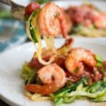 a fork full of zucchini noodles and a cooked shrimp