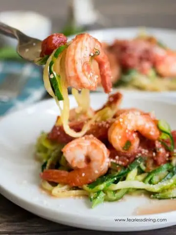 a fork full of zucchini noodles and a cooked shrimp