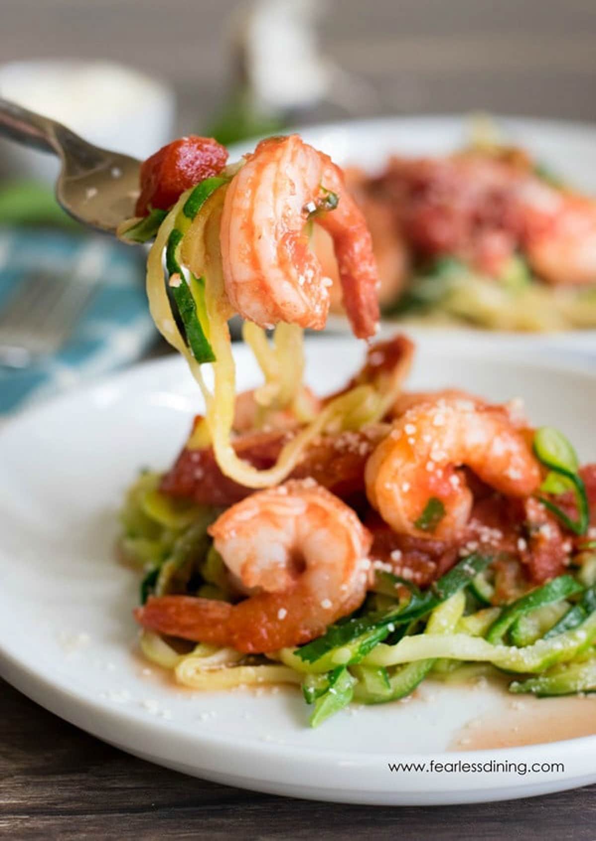 A fork full of zucchini noodles and a cooked shrimp.