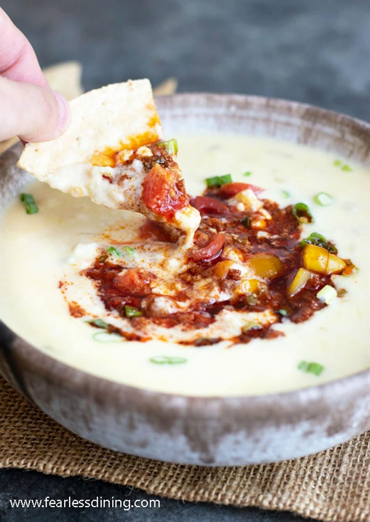 Stirring the chorizo into the queso with a tortilla chip.