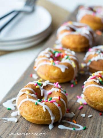 vanilla donuts with icing and rainbow sprinkles on a cutting bord