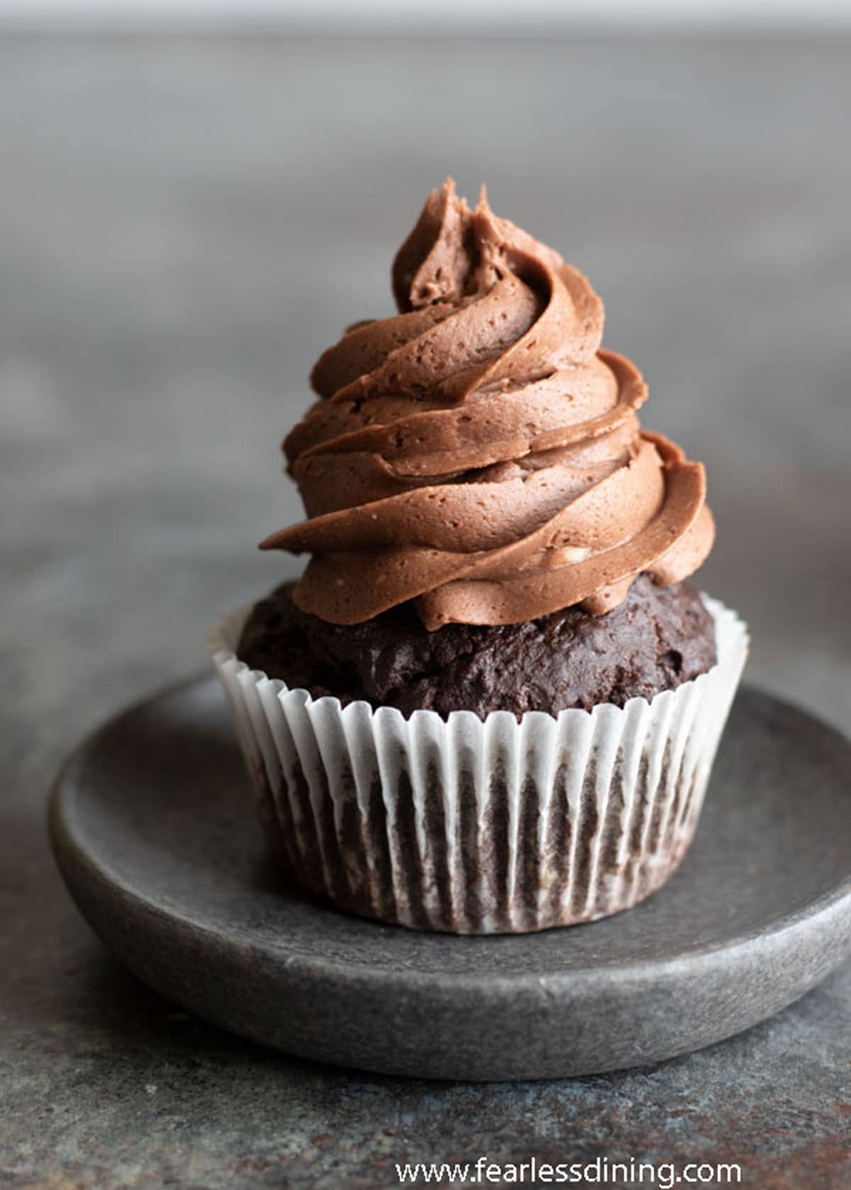 A single chocolate cupcake on a charcoal grey plate.