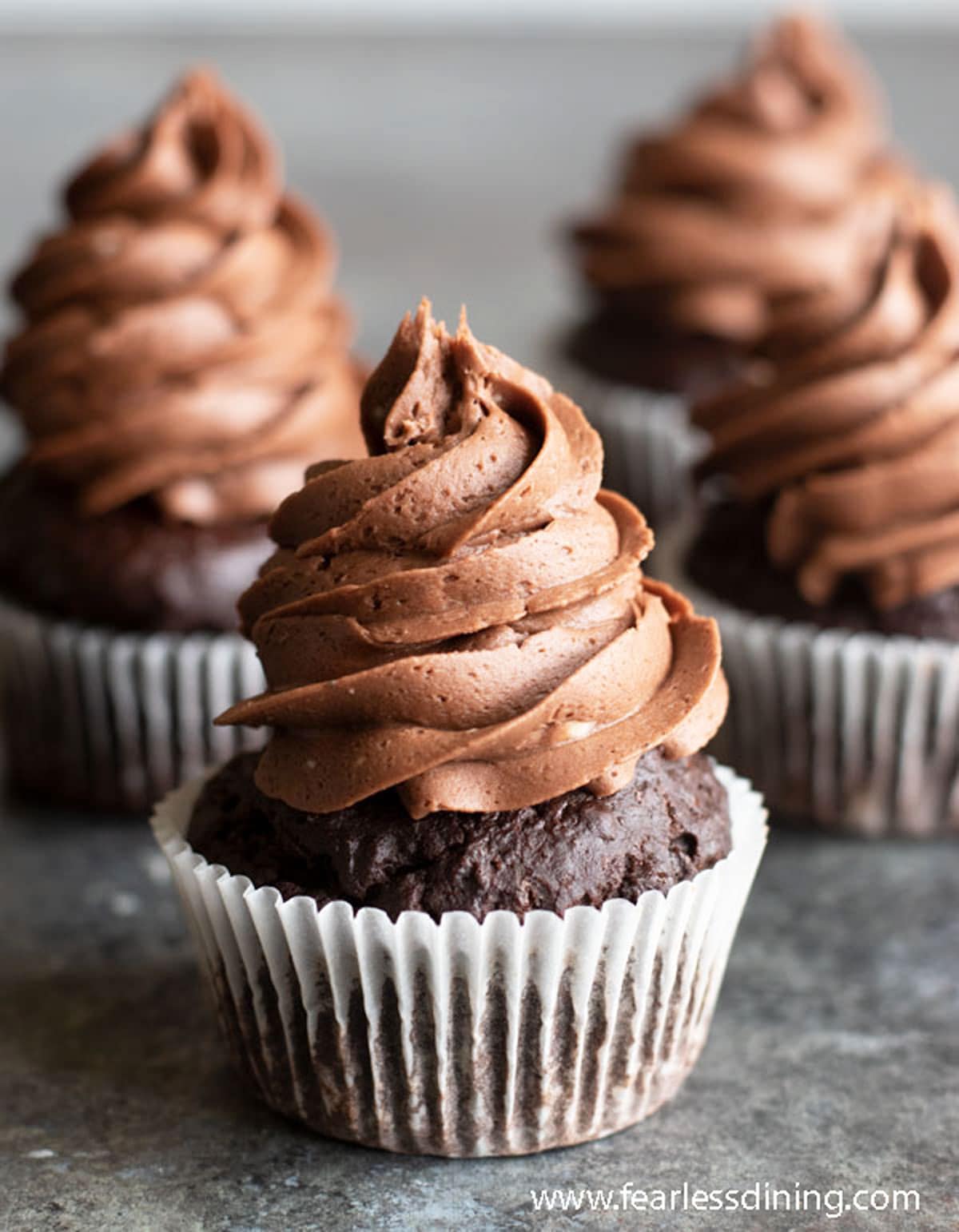 Three frosted cupcakes on the counter.