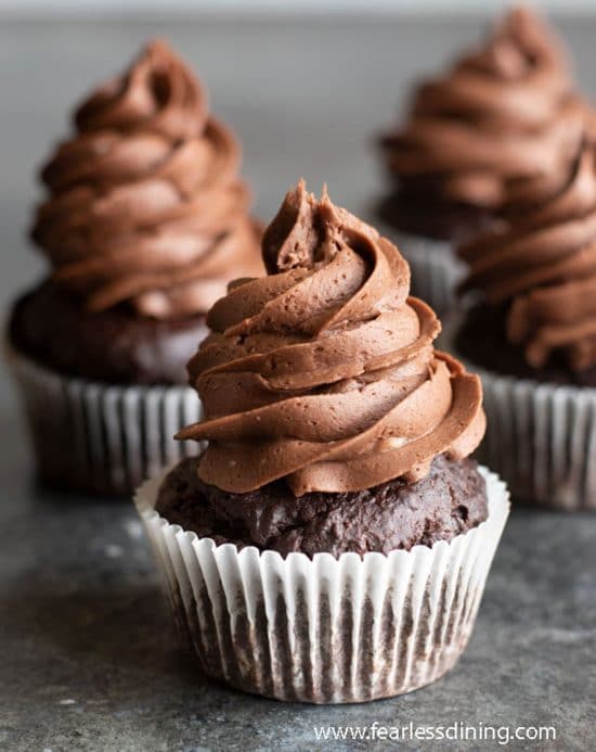 Rows of chocolate frosted cupcakes on the counter.