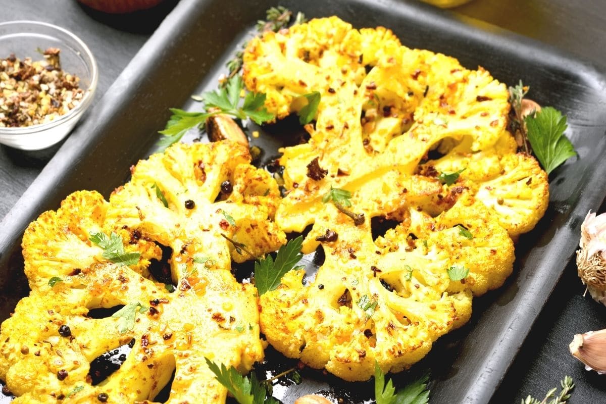 Turmeric cauliflower steaks on a baking sheet.