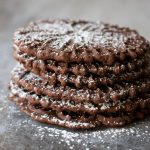 A stack of five chocolate pizzelle cookies.