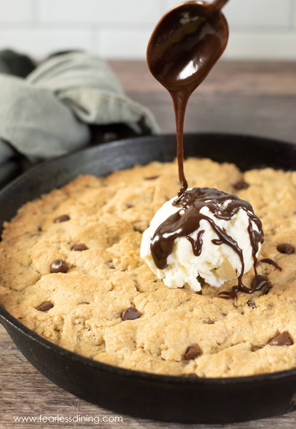 Drizzling hot fudge over the skillet cookie.