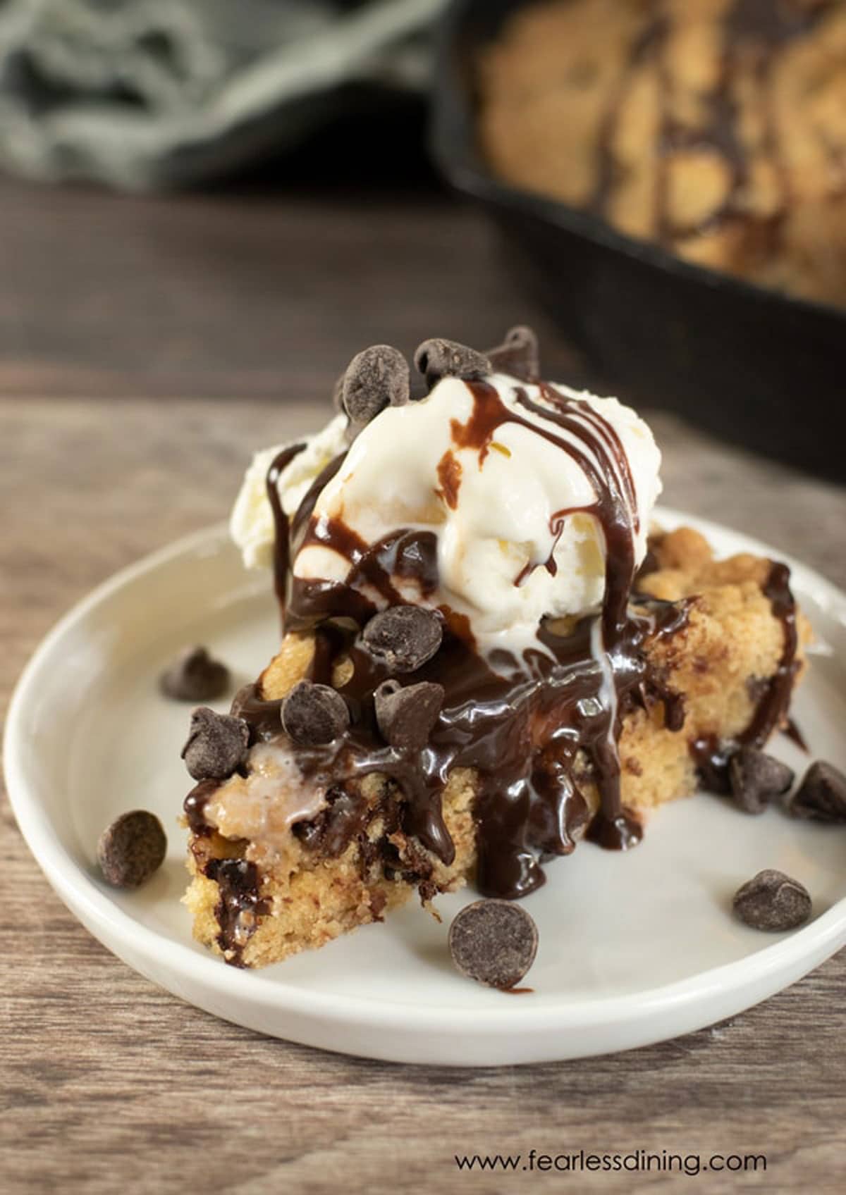 A slice of gluten free skillet cookie topped with ice cream an hot fudge.