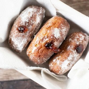 Three gluten free jelly filled donuts in a basket.
