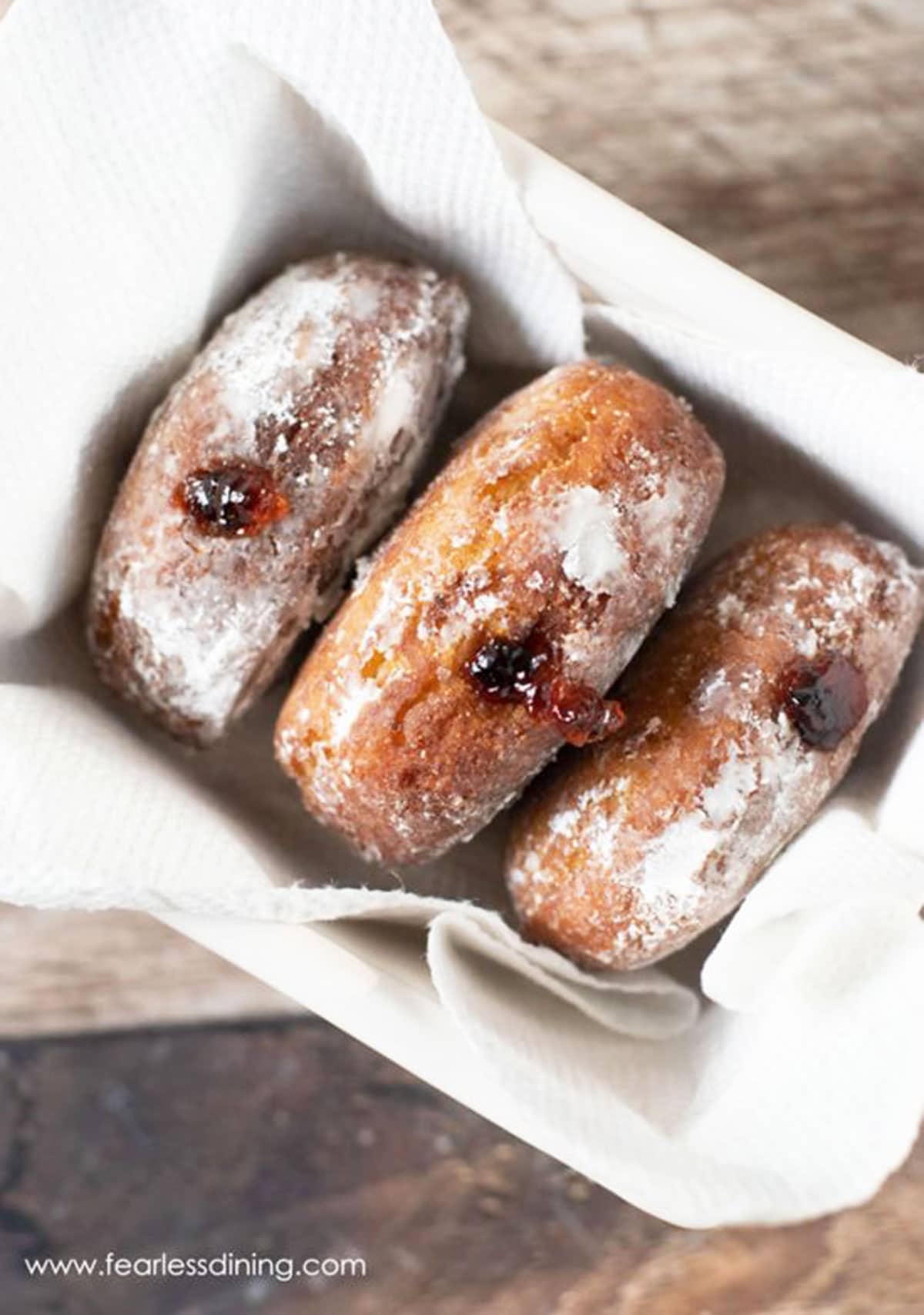 Three gluten free jelly donuts in a basket.