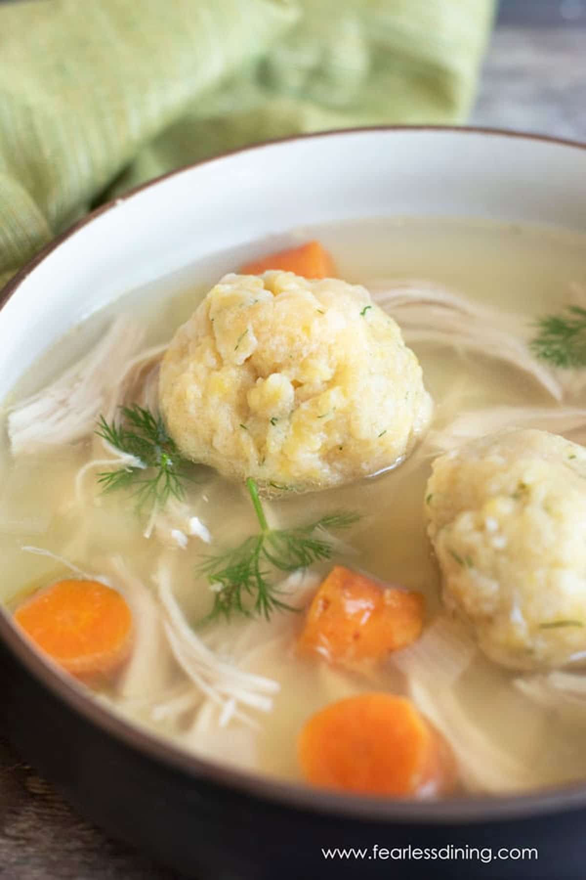 A close up of a bowl of matzo ball soup.