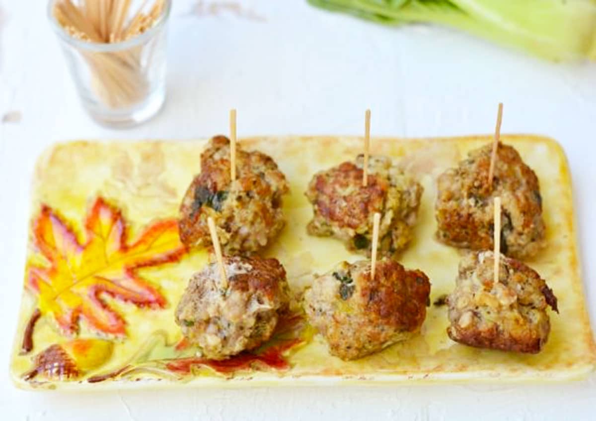 A platter filled with meatballs. Each meatball has a toothpick in it.