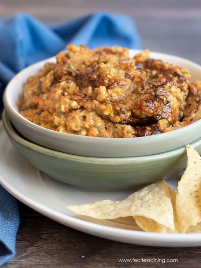 A bowl of eggplant dip with tortilla chips.