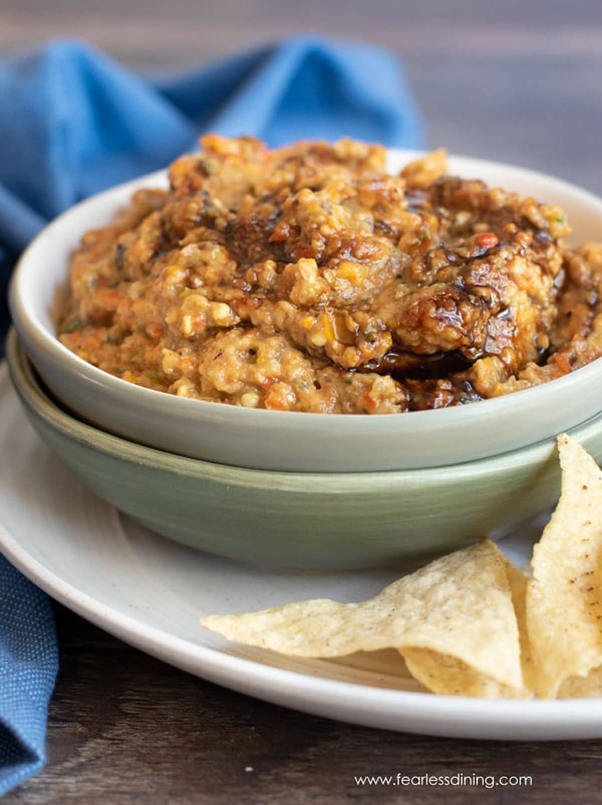 A bowl of eggplant dip with tortilla chips.