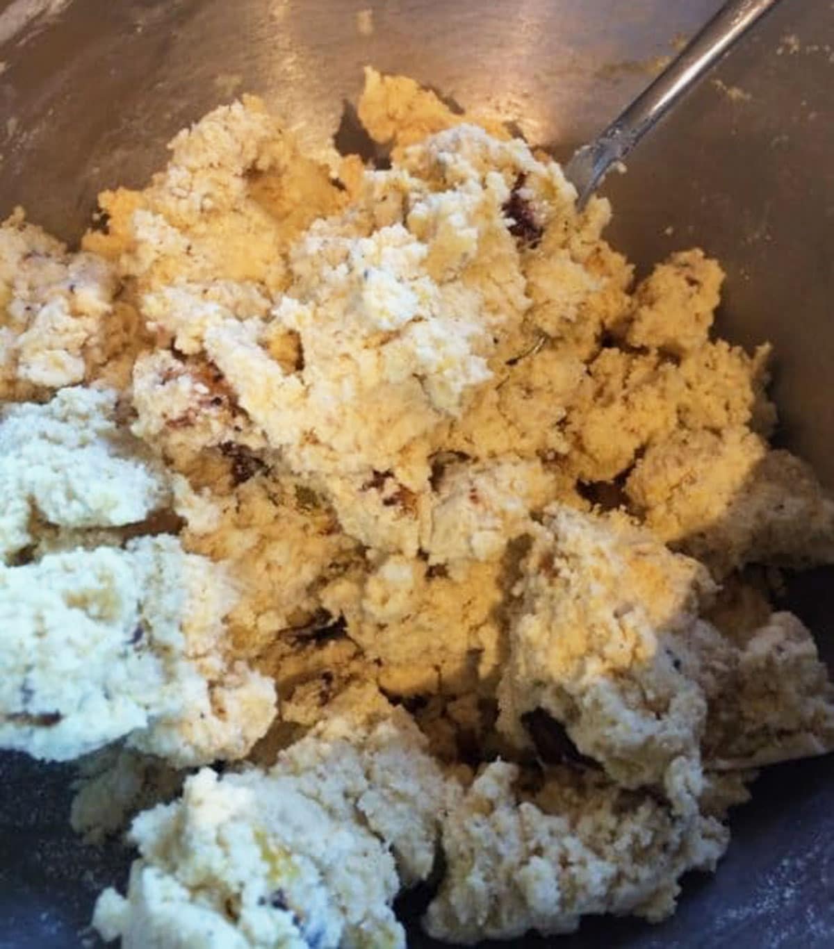Cornmeal scones dough in a metal mixing bowl.