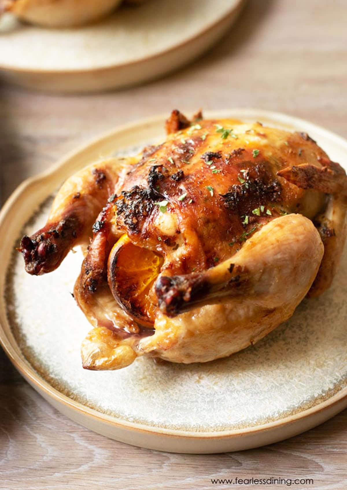 A roasted cornish game hen on a large plate.