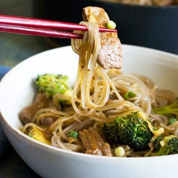 chopsticks holding up beef and noodles