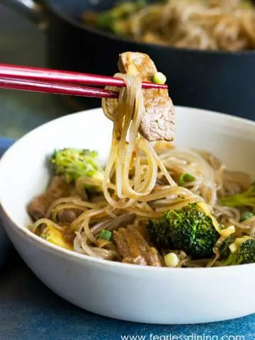 chopsticks holding up beef and noodles