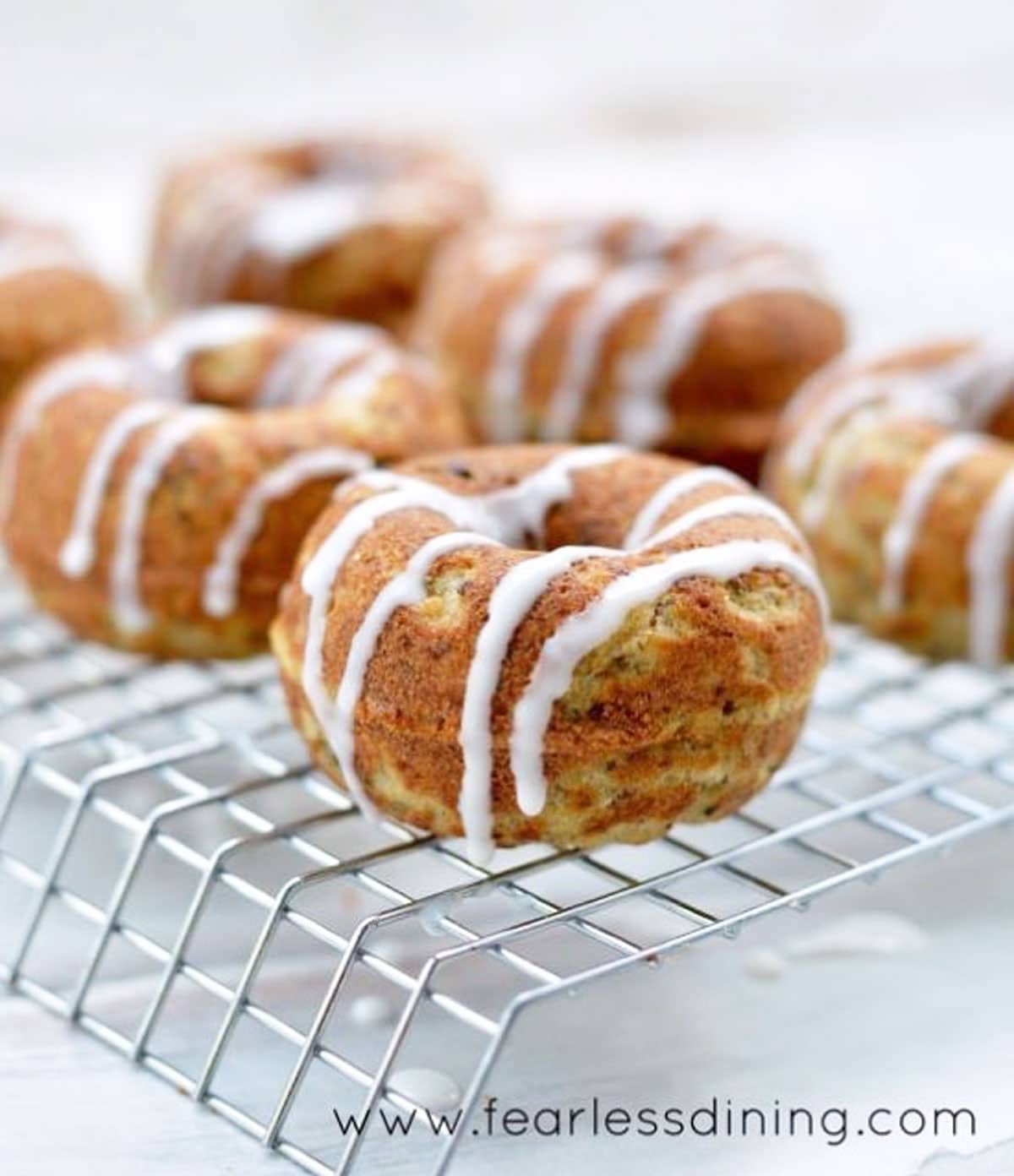 Gluten free donuts on a rack with an icing drizzle.