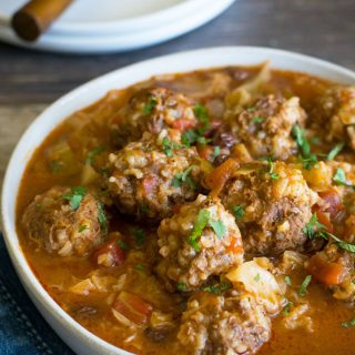 A serving bowl filled with cabbage and meatballs.