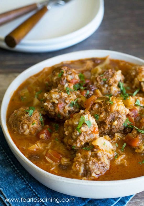 A serving bowl filled with cabbage and meatballs.