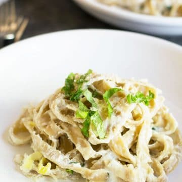 A plate of fettuccine alfredo topped with fresh basil.