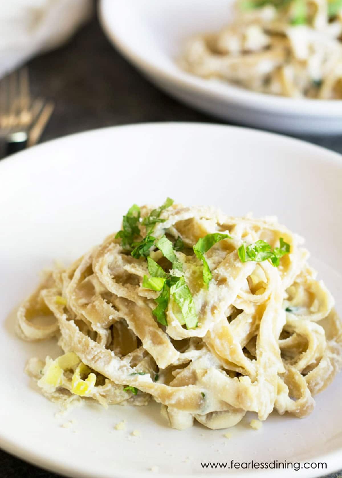 A plate of fettuccine alfredo topped with fresh basil.