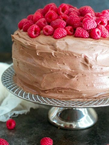 a frosted chocolate cake topped with fresh raspberries