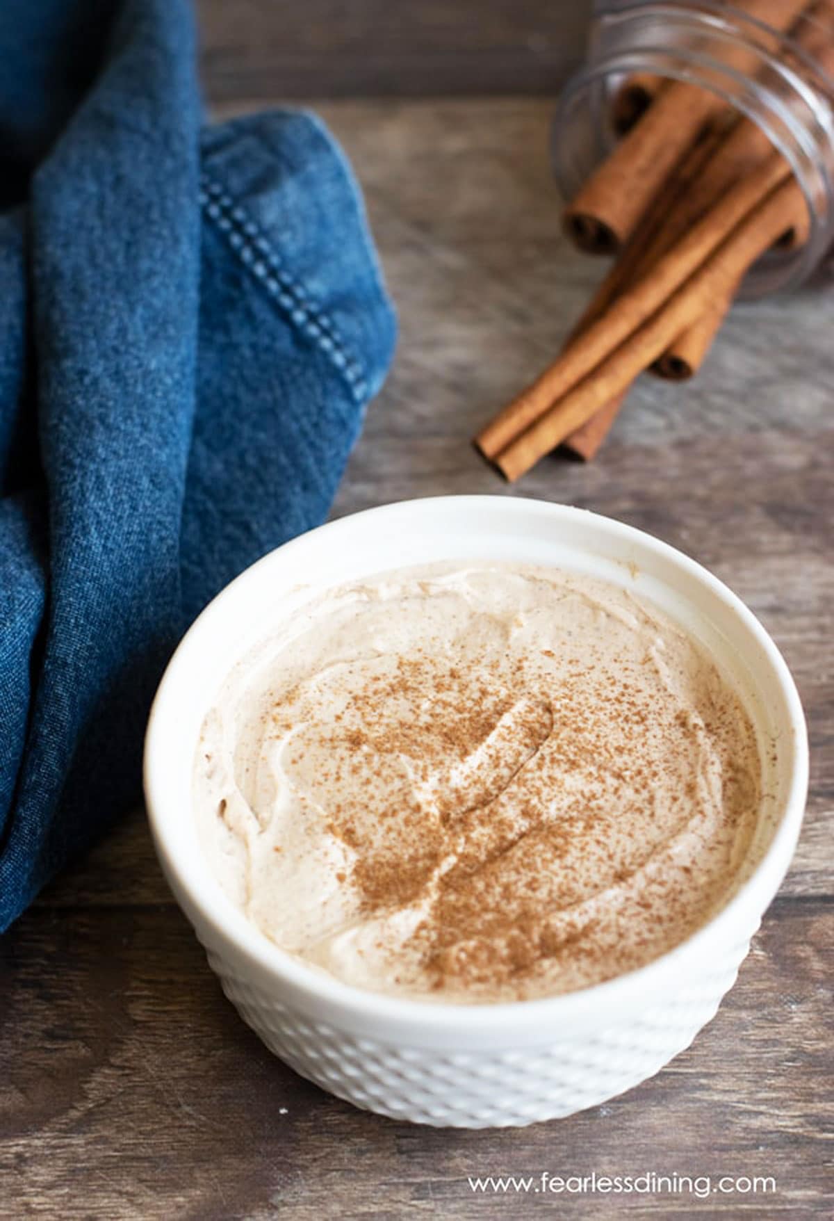 A white bowl filled with cinnamon flavored cream cheese.