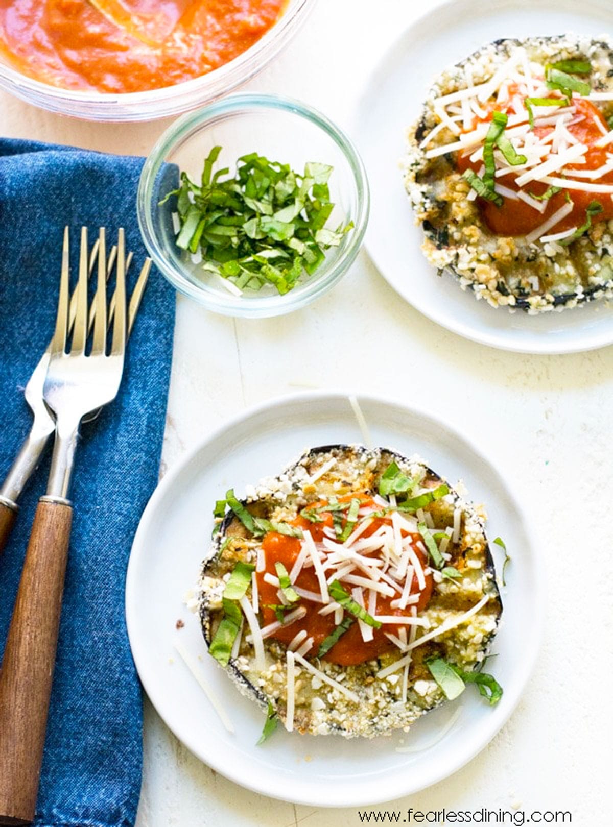 The top view of two plates with crispy eggplant parmesan.