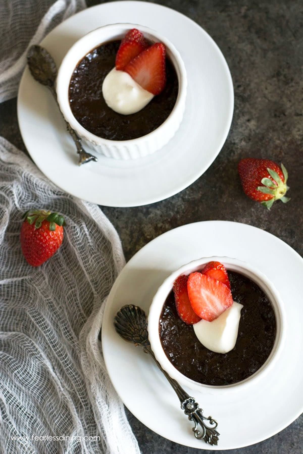 The top view of two ramekins filled with chocolate custard on a table.