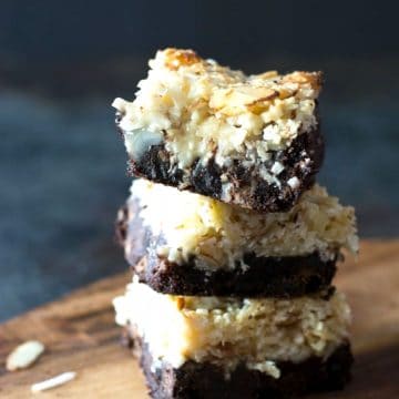A stack of three almond joy bars on a wooden cutting board.