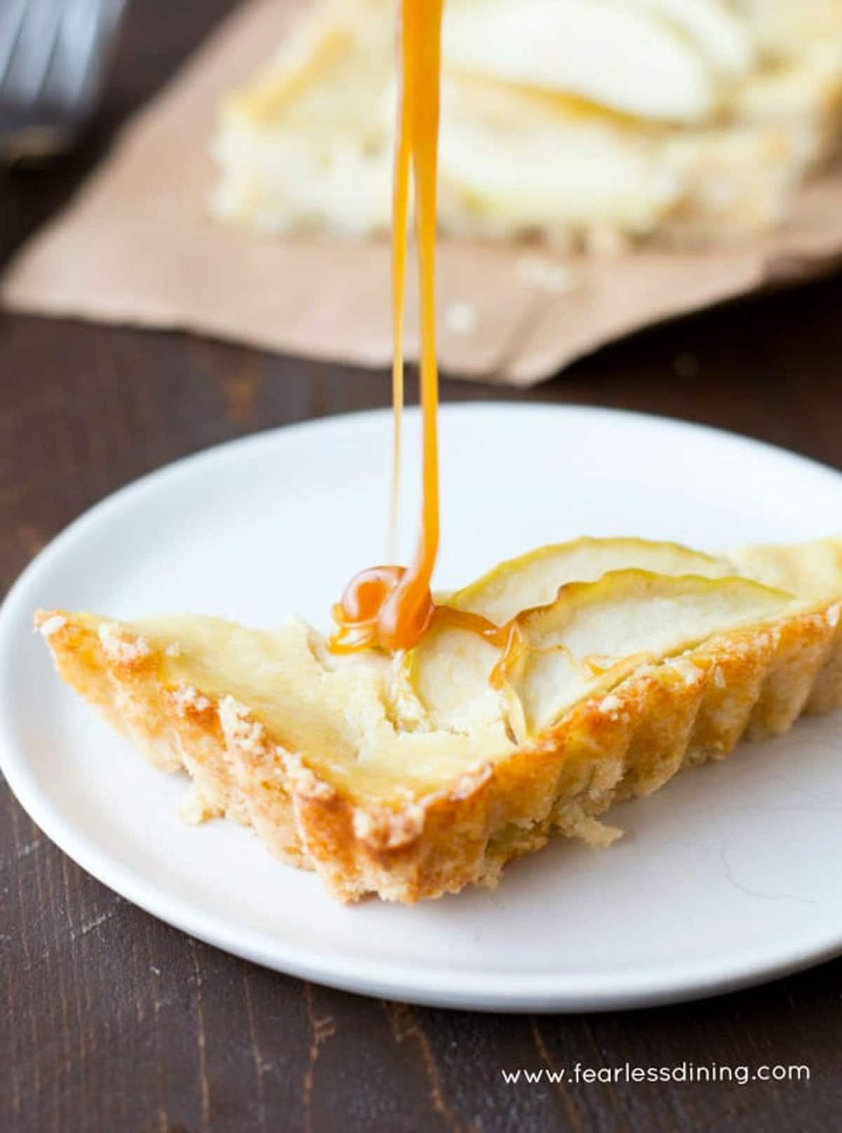 Drizzling caramel over a slice of apple tart.