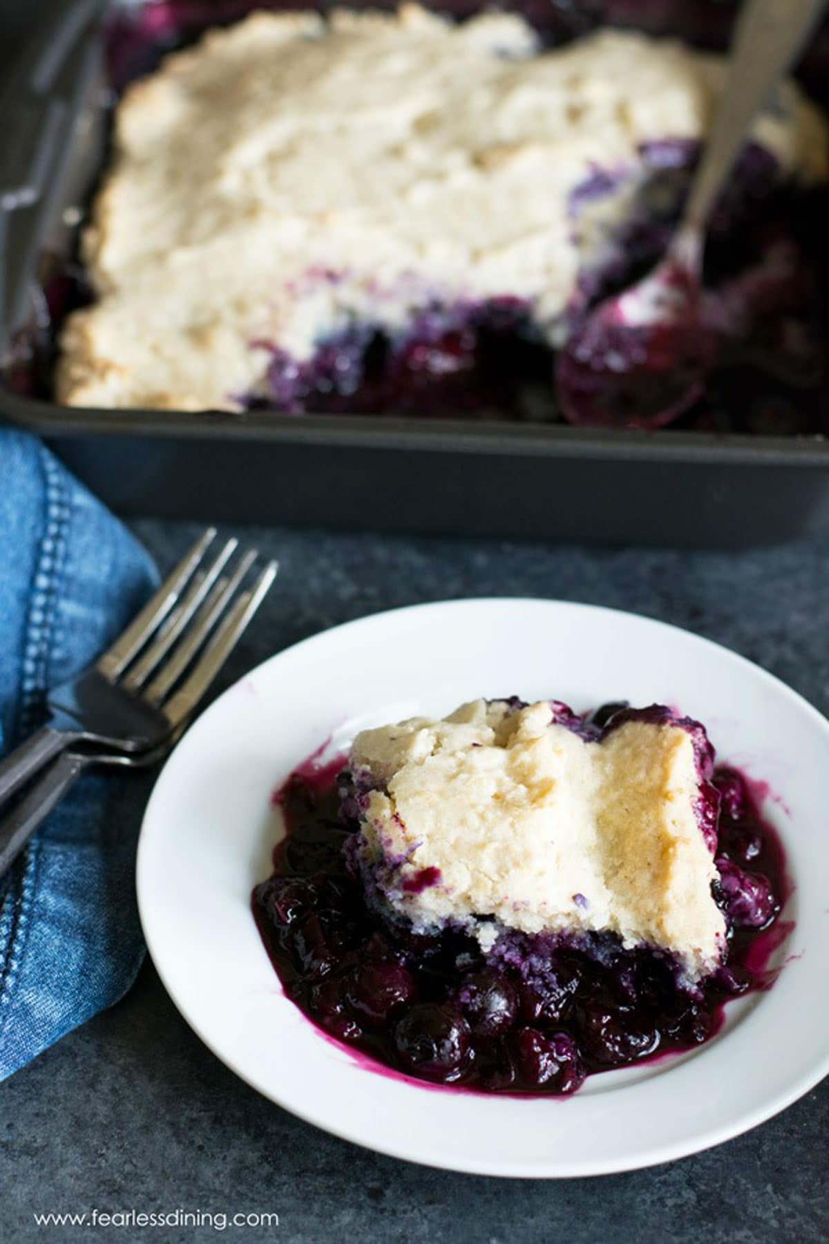 A small white plate filled with gluten free blueberry cobbler.