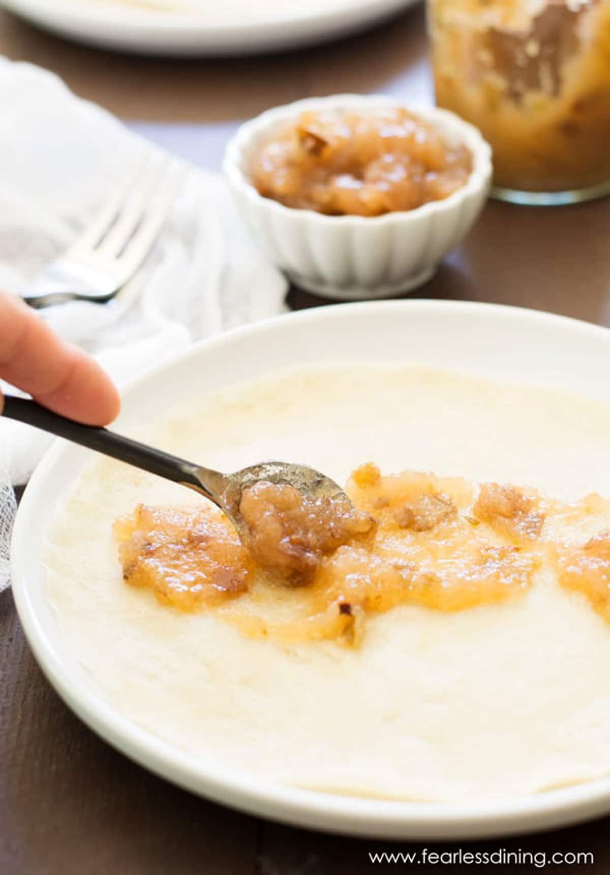 Spreading pear jam onto a crepe.