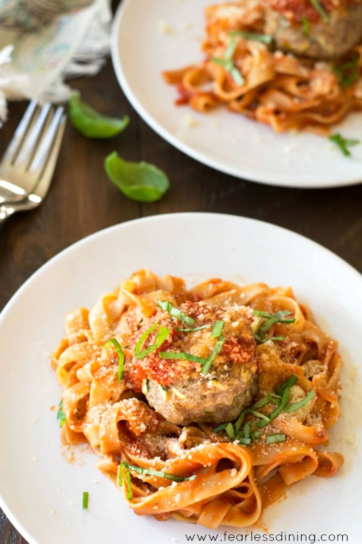 The top view of two plates full of spaghetti and meatballs.